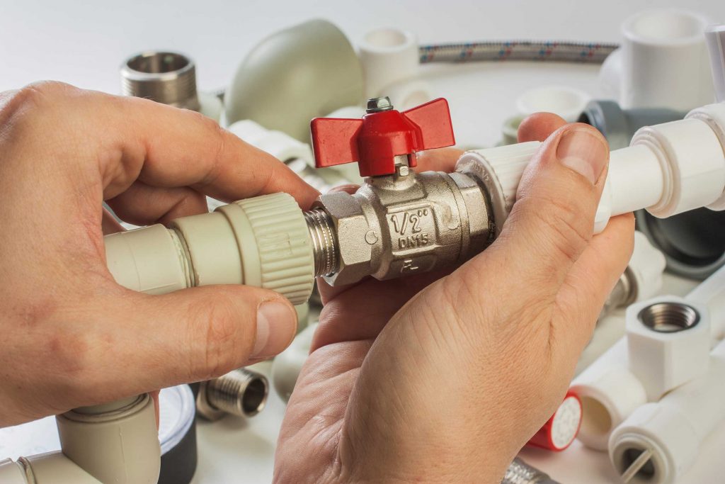 Installateur montiert ein Kugelventil an einer Wasserleitung